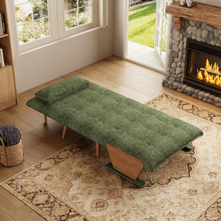 A fully flattened sage green tufted fabric convertible sofa bed rests on a patterned area rug in a cozy living room. A matching pillow is positioned neatly at the head of the bed. In the background, open glass doors reveal a green garden view next to a warm stone fireplace, completing the inviting interior.