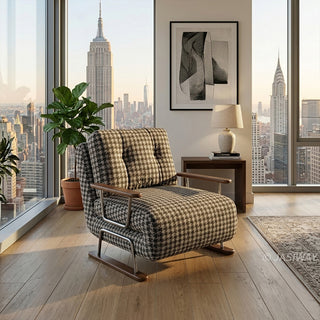 A black and white houndstooth pattern convertible sleeper sofa armchair featuring metal and wood-trimmed arms in a luxury New York high-rise apartment with floor-to-ceiling city skyline views, a potted plant, and a modern side table with a lamp.