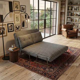 A brown and white houndstooth pattern convertible sleeper sofa reclined into a chaise lounge in a sophisticated living room featuring a gallery wall, an arched floor lamp, a patterned area rug, and large industrial-style windows.