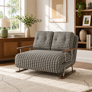 A brown and white houndstooth pattern convertible sleeper sofa loveseat featuring metal and wood-trimmed arms in a bright living room with a textured area rug, wooden sideboard with a green lamp, and a bookshelf.