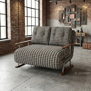 A brown and white houndstooth pattern convertible sleeper sofa loveseat featuring metal and wood-trimmed arms in an industrial loft with exposed red brick walls, large windows, concrete flooring, and metal wall art.