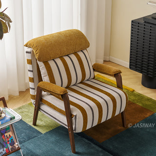 A yellow-and-white striped convertible armchair is positioned on a colorful block-patterned rug in a brightly lit room. A matching striped lumbar pillow and a plush yellow headrest rest against its back, complemented by wooden armrests and legs. In the background, sheer white curtains, a dark modern media cabinet, and a small glass side table complete the interior setting.