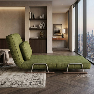 A profile view of a modern convertible green textured fabric lounge chair is positioned centrally on a patterned rug. The lounge features an adjustable backrest with an attached lumbar pillow and rests on distinctive chrome and dark wood sled-style legs. In the background, a luxurious apartment living space includes a built-in bookshelf, a console table, and floor-to-ceiling windows offering a panoramic New York City skyline view at dusk. A blanket is draped on a side table to the left.