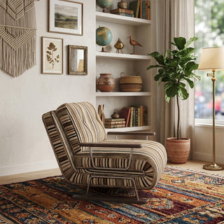 A modern armchair upholstered in a warm brown, black, and beige striped fabric is positioned on a vibrant, patterned bohemian area rug over a wooden floor. The chair features button-tufted back cushions, wooden armrests, and a sleek sled base. In the background, a bohemian-style room with a macrame wall hanging, built-in bookshelves filled with books and globes, a potted fiddle-leaf fig, and a standing lamp completes the warm, eclectic decor.