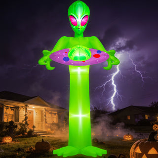 Giant Halloween inflatable green alien holding a UFO spaceship yard decoration with glowing pink eyes and internal LED lights, displayed on a spooky suburban front lawn under a dramatic stormy night sky with lightning.