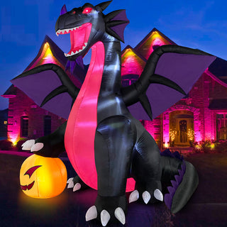 Illuminated nighttime outdoor display of a large Halloween inflatable black and purple dragon featuring glowing red eyes and a bright pumpkin in front of a house.