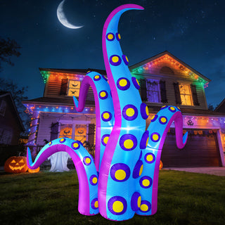 Giant Halloween inflatable blue and purple monster tentacle yard decoration glowing with built-in LED lights at night on a front lawn in front of a suburban house under a crescent moon.