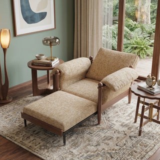 Lifestyle staging shot of a convertible accent armchair with its pull-out footrest extended, featuring beige textured fabric and dark wood framing in a living room.