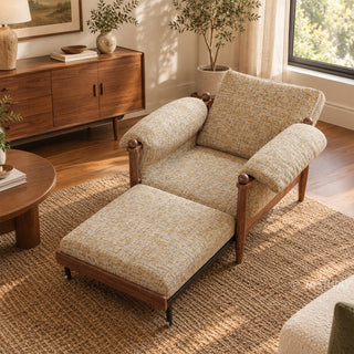 High-angle lifestyle staging shot of a convertible accent armchair with its integrated pull-out footrest extended, featuring textured beige fabric and dark wood framing in a sunlit living room.