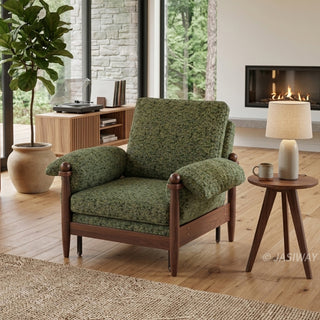 Lifestyle staging shot of a green textured accent armchair featuring dark wood framing and plush cushions in a modern living room with a fireplace.