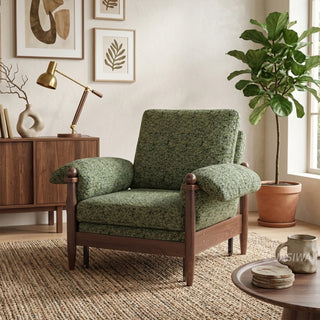 Lifestyle staging shot of a green textured fabric accent armchair with dark wood framing in an art-filled living room.