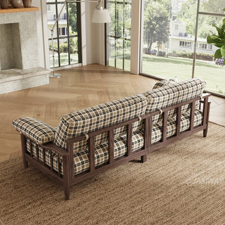 High angle back view of a plaid fabric sofa with dark wood spindle frame on a textured rug