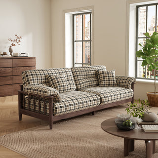 Three-quarter angle view of a plaid fabric sofa with dark wood frame in a modern living room with coffee table