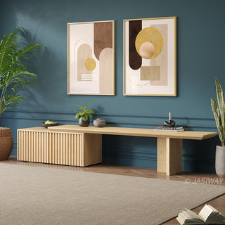 A modern wooden media console with slatted paneling is set against a dark teal wall. Above the console hang two framed abstract art prints featuring geometric shapes in neutral and golden tones. The floor is covered by a light-colored area rug, complemented by potted plants on either side of the unit. Small decorative items, books, and a bowl of fruit adorn the surface of the cabinet, creating a stylish and balanced interior.