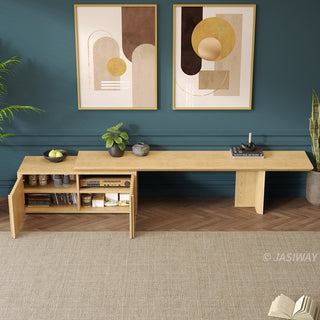 A modern wooden media console is positioned against a dark teal wall, with its cabinet doors open to display interior shelving filled with items. Above the unit, two framed abstract art prints feature geometric shapes in neutral and golden tones. Potted plants flank the setup, while a light-colored area rug rests on the herringbone wooden floor in the foreground.