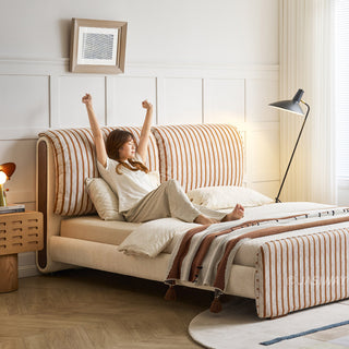JASIWAY modern luxury upholstered platform bed frame featuring a curved wingback shelter headboard and premium textured chenille fabric upholstery in a neutral, multi-toned weave, available in queen and king sizes for high-end contemporary bedroom interiors.-Three quarter view with model stretching