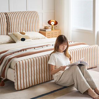 JASIWAY modern luxury upholstered platform bed frame featuring a curved wingback shelter headboard and premium textured chenille fabric upholstery in a neutral, multi-toned weave, available in queen and king sizes for high-end contemporary bedroom interiors.-Medium shot with model sitting on the floor