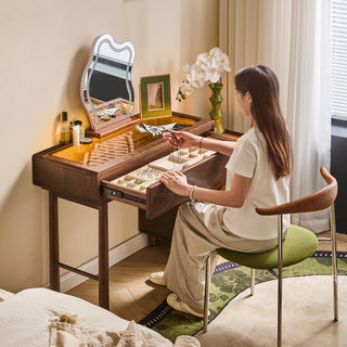 JASIWAY solid wood extendable vanity desk featuring a rich walnut-grain finish, a three-drawer side storage cabinet ,and a decorative tempered glass top, specifically engineered for luxury small-space interiors.-High-angle view with model sitting