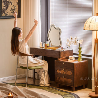 JASIWAY solid wood extendable vanity desk featuring a rich walnut-grain finish, a three-drawer side storage cabinet ,and a decorative tempered glass top, specifically engineered for luxury small-space interiors.-Three-quarter view with model sitting