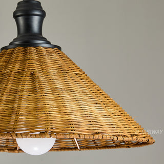 This is a close-up detail shot of a pendant lamp featuring a conical, woven rattan shade. The textured, natural-fiber shade is attached to a solid black mounting fixture. A plain white light bulb is visible underneath, contrasting with the warm, organic look of the wicker material.