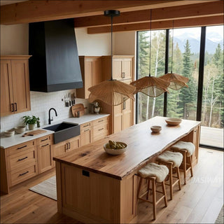 The space is defined by light wood cabinetry, exposed ceiling beams, and a large live-edge wood island that is complemented by three stools topped with fuzzy white cushions. Three distinctive, flower-shaped woven pendant lights hang over the island, drawing the eye. A large floor-to-ceiling window wall reveals a stunning, panoramic view of a dense forest and mountains, flooding the room with natural light.