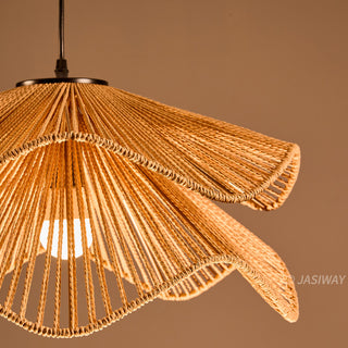This close-up shot highlights the intricate craftsmanship of a natural fiber rope pendant light, showcasing its sculptural, double-layered design. The wave-like silhouette and warm, earthy tones create a sophisticated organic aesthetic that adds textural depth to any interior. The interplay of light through the rope detailing casts a gentle, inviting glow, perfect for a curated, modern living space.