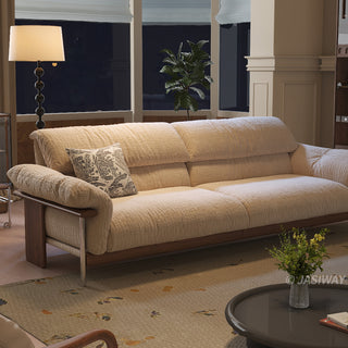 JASIWAY mid-century modern 3-seater sofa featuring textured chenille upholstery, sculptural curved armrests with integrated solid wood supports, and a low-profile exposed timber base frame accented by slender polished metal legs.-Three-quarter view at night