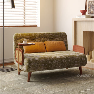 JASIWAY mid-century modern convertible sleeper chair bed upholstered in premium botanical jacquard fabric with olive green palm leaf patterns. Features a space-saving multi-functional design with an integrated swivel wooden side table, woven rattan armrest details, solid wood tapered legs, and a textured mustard lumbar support pillow. Ideal luxury accent sleeper lounger for high-end apartment living and compact spaces.-Three quarter view