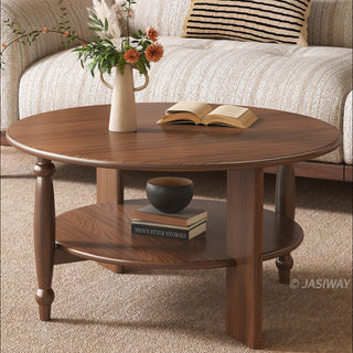 JASIWAY mid-century modern round coffee table set crafted from rich walnut-finished solid wood, a lower open storage shelf holding books, and an architectural leg design with elegant turned wood detailing. The tall, slim accent end table showcases a matching round wooden top supported by a sculptural pedestal base with a dark metal floor plate, styled alongside a warm contemporary living room sofa.-Close-up view