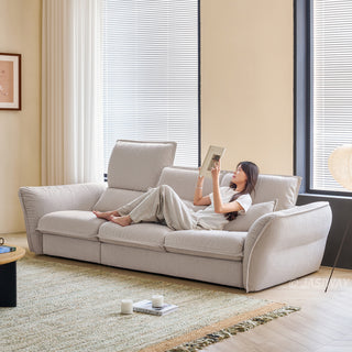 JASIWAY modern 3-seater fabric sofa with adjustable high-back headrests and deep-seated cloud cushions, featuring a low-profile minimalist design and ergonomic neck support with a high-end, contemporary aesthetic for luxury living rooms. -Diagonal view with model leaning against the headrest