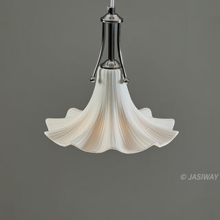 A white, ceramic pendant light is shown against a neutral grey background, featuring a gracefully fluted shade that resembles a blooming flower. A polished chrome fixture connects the ceramic shade to the ceiling, providing an elegant contrast to the soft, organic shape of the light.