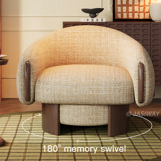 A beige textured barrel armchair with dark wood accents on its curved armrests sits centered on a round, green-patterned rug. The modern accent chair features a robust wooden swivel base. A white circular graphic overlay with arrows and the text "180° memory swivel" highlights its rotating function. In the background, a dark wood cabinet with various decorative objects is visible.