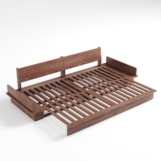 A studio product shot displays an extended dark walnut wood sofa bed frame on a plain white background. The frame features a slatted wooden sleeping surface and two upright backrest panels. Attached side compartments are built into both ends of the minimalist wooden structure.