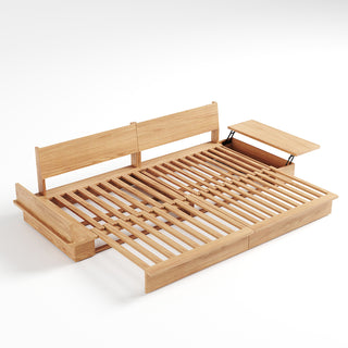 A studio product shot displays an extended light wood sofa bed frame on a plain white background. The frame features a slatted wooden sleeping surface and two upright backrest panels. Side tables with hinges are attached to the ends, with one open to reveal storage compartments beneath.