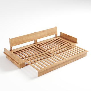 A studio product shot displays an extended light wood sofa bed frame on a plain white background. The frame features a slatted wooden sleeping surface and two upright backrest panels. Attached side compartments are built into both ends of the minimalist wooden structure.