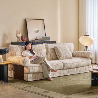 JASIWAY textured linen blend sofa, featuring a minimalist upholstery with a subtle linear weave, highlighting its plush, oversized bolsters and the architectural solid wood side panels, perfect for contemporary living rooms.-Three-quarter view with model sitting