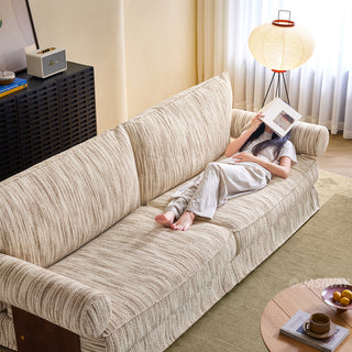 JASIWAY textured linen blend sofa, featuring a minimalist upholstery with a subtle linear weave, highlighting its plush, oversized bolsters and the architectural solid wood side panels, perfect for contemporary living rooms.-High-angle view with model lying