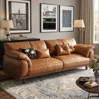 JASIWAY mid-century modern 3-seater sofa featuring premium top-grain leather upholstery with hand-stitched detailing, plush oversized armrests, and a sturdy solid wood exposed frame base in a walnut finish for a luxury living room aesthetic.-Three-quarter view