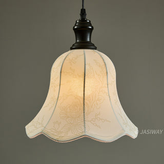 A delicate pendant light features a scalloped, bell-shaped shade adorned with a subtle, intricate floral pattern. The soft fabric diffuses light beautifully, creating a warm and inviting glow against the simple black fixture. This piece highlights a blend of classic charm and understated design, perfect for adding a touch of elegance to any interior.