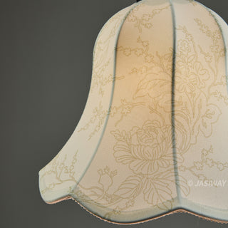 This close-up view highlights the delicate fabric shade of a pendant light, featuring an intricate, soft floral pattern. The scalloped edges and light-diffusing material create a warm, inviting glow that emphasizes its refined, artisan-quality design. It serves as a subtle yet elegant accent, perfect for adding a touch of sophisticated charm to a curated interior space.