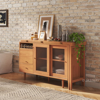 Close-up lifestyle shot of a modern natural wood sideboard cabinet with fluted glass doors and a hanging plant styling against an exposed brick wall.