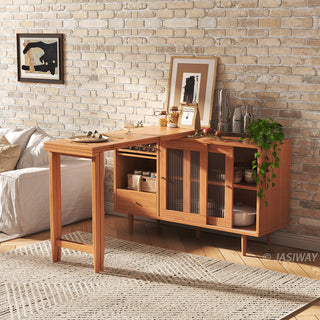 Wide-angle lifestyle shot of a modern natural wood extendable dining table set with fluted glass doors on a sideboard, staged against an exposed brick wall with cozy apartment decor.