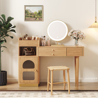 Angled lifestyle view of a modern wooden vanity desk with an illuminated round mirror, fluted cabinet doors, and a matching stool in a warm bedroom setting.