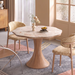 Modern Japandi round dining table featuring a scalloped wave-edge marble top and wooden flared pedestal base, styled with textured dining chairs on a geometric rug.