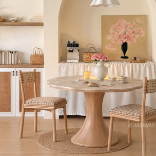 Modern French cream style scalloped wave-edge round marble bistro dining table with a wooden pedestal base and two plaid chairs in a cozy arched dining nook.