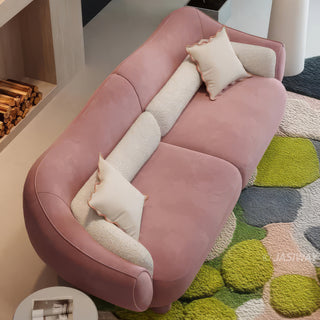 RINGCHEN modern luxury blush pink curved cloud sofa featuring a sculptural shell-inspired silhouette, premium deep-seat upholstered velvet fabric with decorative cream boucle lumbar pillows and ruffled accent cushions for a high-end designer living room aesthetic.-High-angle view
