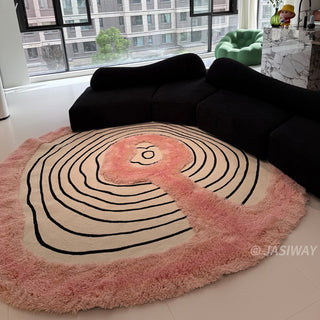 RINGCHEN petal pink and obsidian abstract round rug featuring a high-low tufted texture and organic circular ripples, showcases a hand-drawn tree ring motif with soft pink shaggy edges and crisp black line, blending modern minimalism with poetic visual storytelling.-High-angle wide view