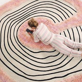 RINGCHEN petal pink and obsidian abstract round rug featuring a high-low tufted texture and organic circular ripples, showcases a hand-drawn tree ring motif with soft pink shaggy edges and crisp black line, blending modern minimalism with poetic visual storytelling.-High-angle view