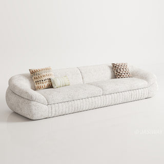 RINGCHEN modern curved cloud sofa featuring premium blush textured upholstery, highlighted by its signature sculptural low-profile silhouette, channel-tufted base detailing, and deep-seated organic cushioning for a high-end minimalist living room aesthetic.-Three quarter studio view