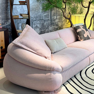 RINGCHEN modern curved cloud sofa featuring premium blush textured upholstery, highlighted by its signature sculptural low-profile silhouette, channel-tufted base detailing, and deep-seated organic cushioning for a high-end minimalist living room aesthetic.-Diagonal view
